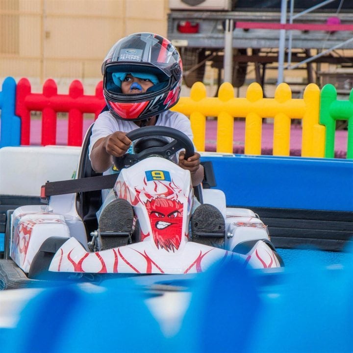 A child in a helmet driving a go-kart